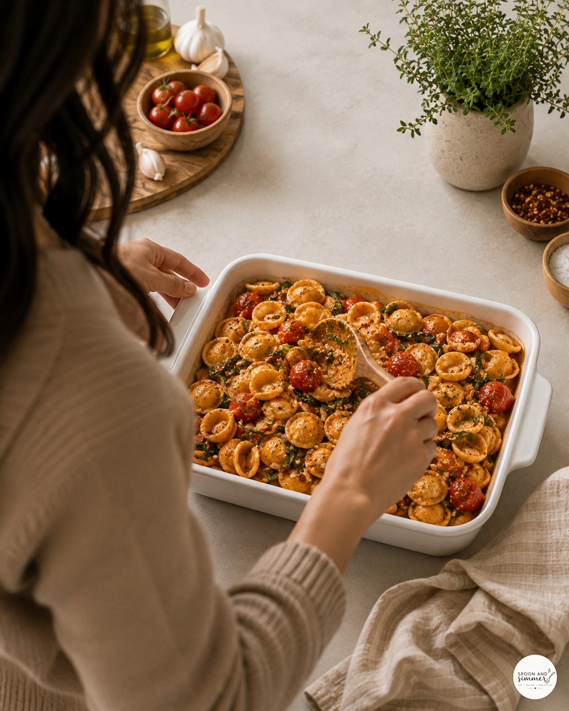 Folding pasta into creamy sauce for baked feta pasta with spinach until glossy