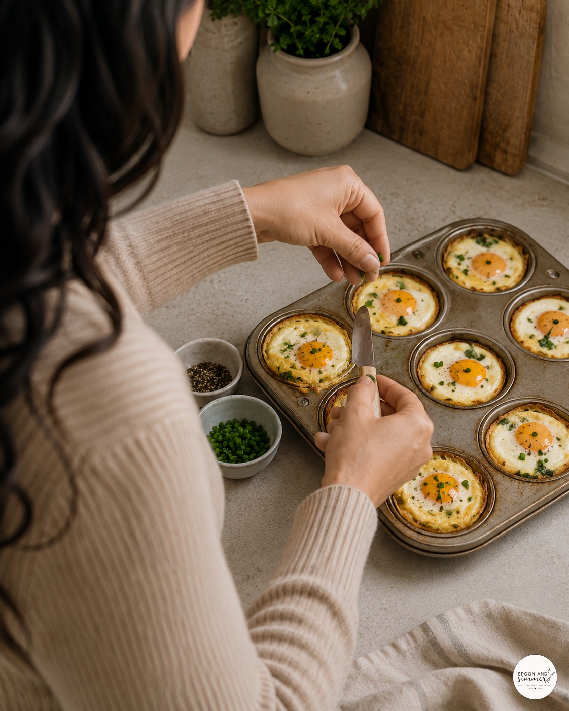 Garnishing baked French eggs with chives and pepper straight from the muffin tin