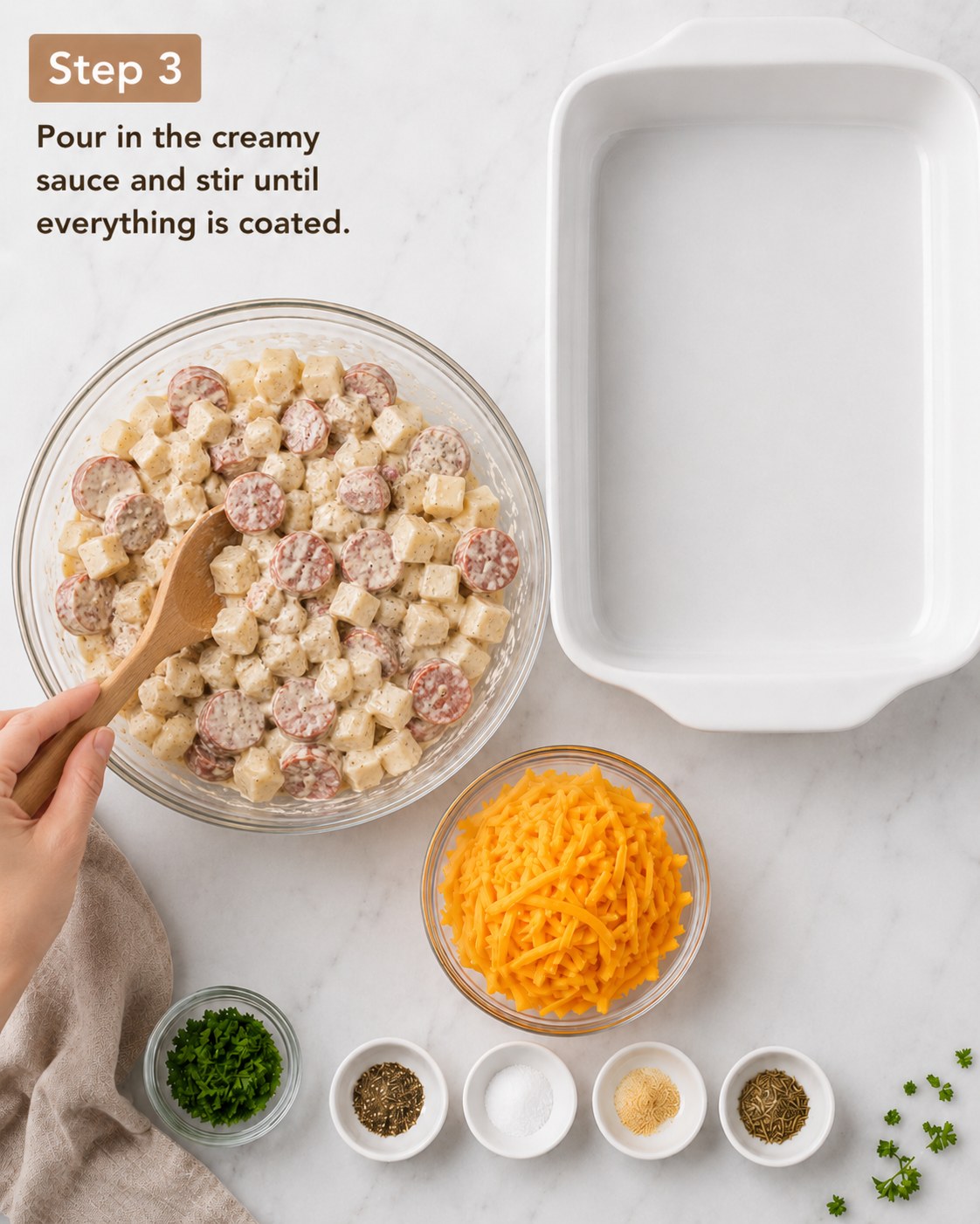 Creamy sauce being stirred into potatoes and sausage for cheesy potato sausage casserole