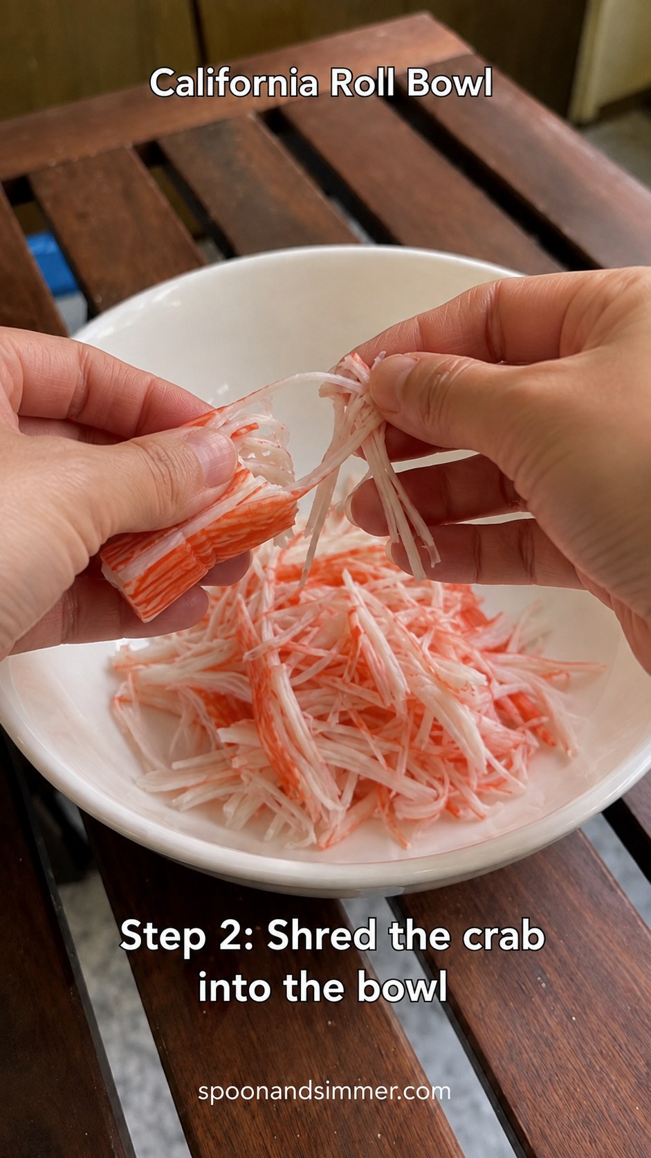 Hands shredding imitation crab into thin strands for a California roll bowl
