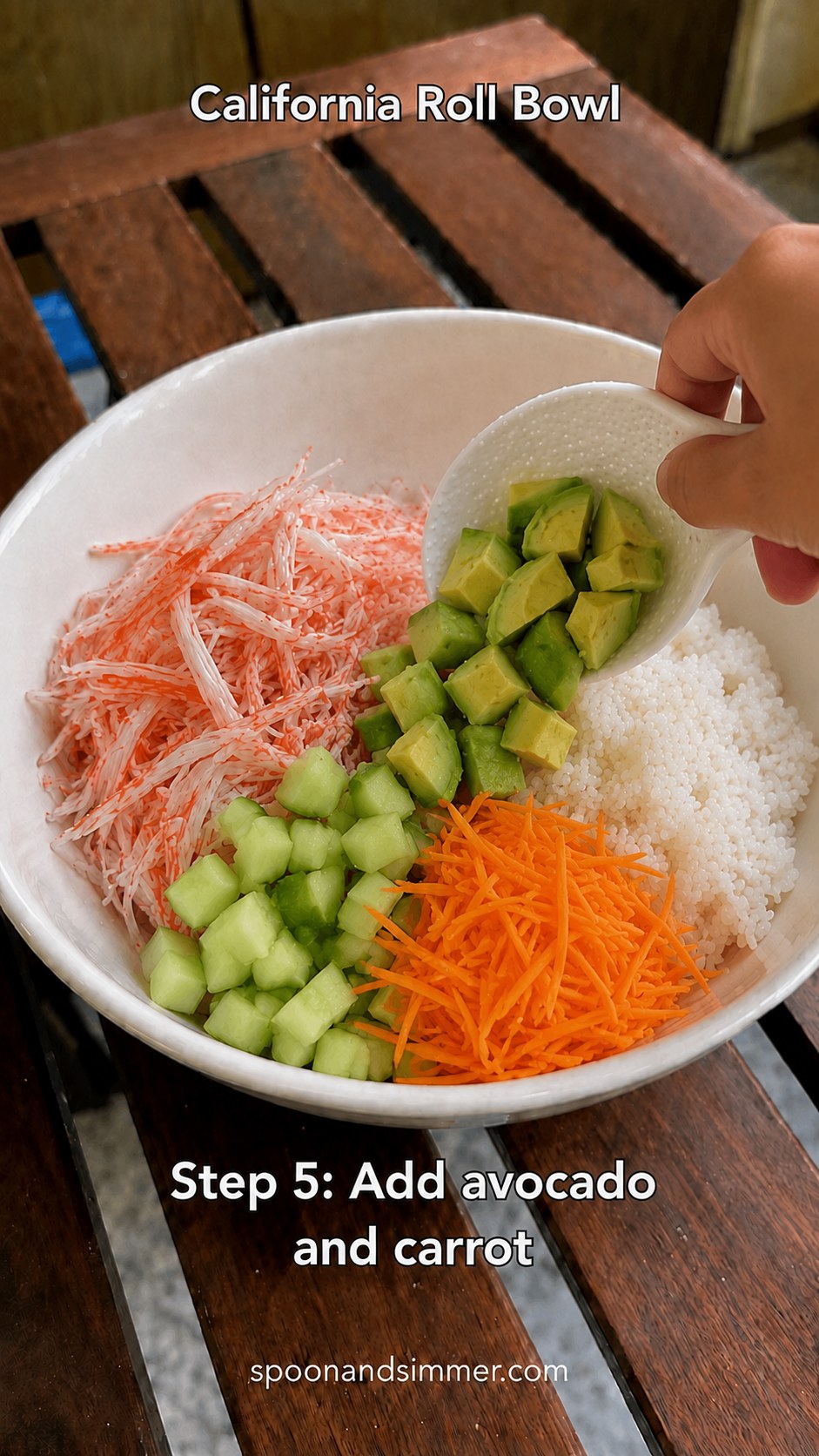Avocado and shredded carrot added to the bowl alongside rice and crab
