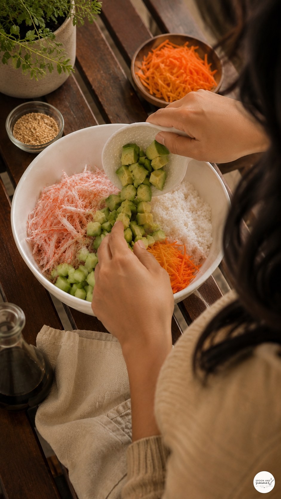 Adding diced avocado to a homemade imitation crab California roll bowl