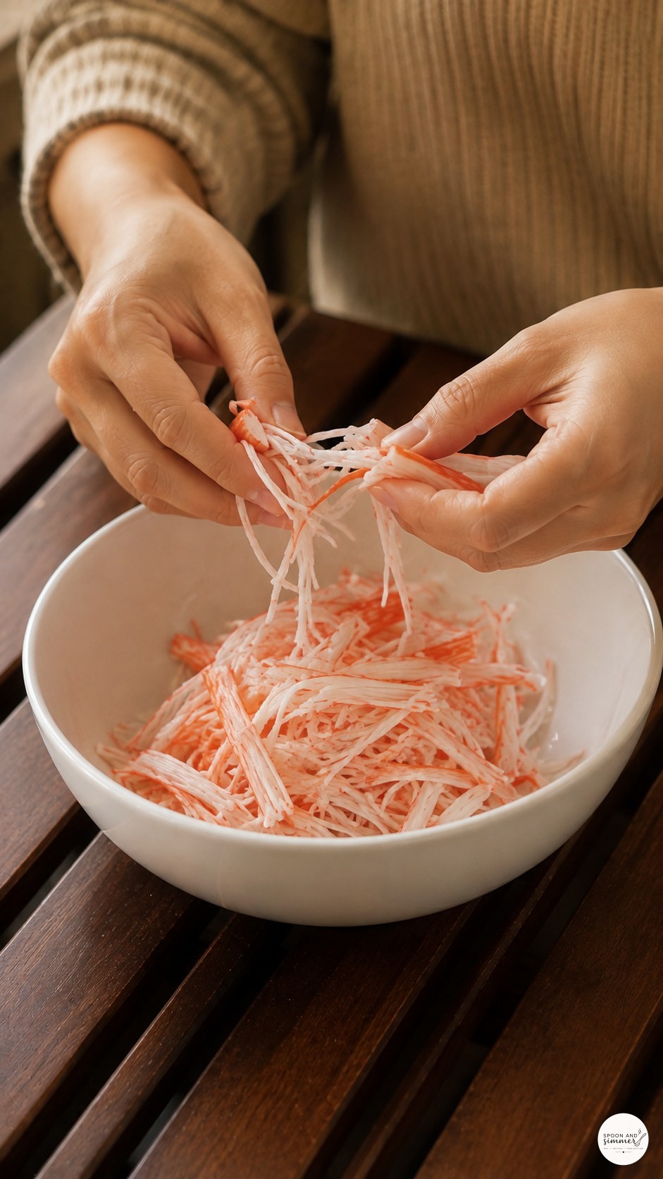 Shredding imitation crab by hand into a bowl for a California roll bowl recipe